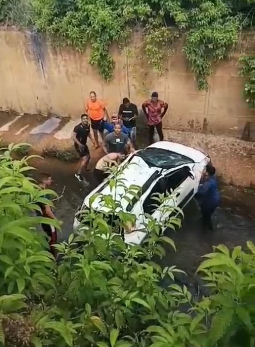 Carro Cai no Córrego e Motorista é Socorrido por Passantes