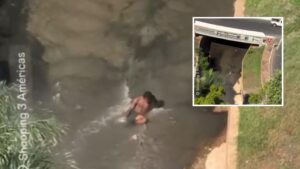 Homem se refresca em córrego urbano durante calor intenso em Cuiabá; veja vídeo