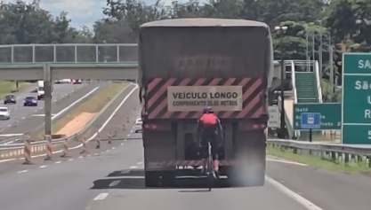 Ciclista desafia a morte ao andar colado na traseira de carreta; Veja vídeo