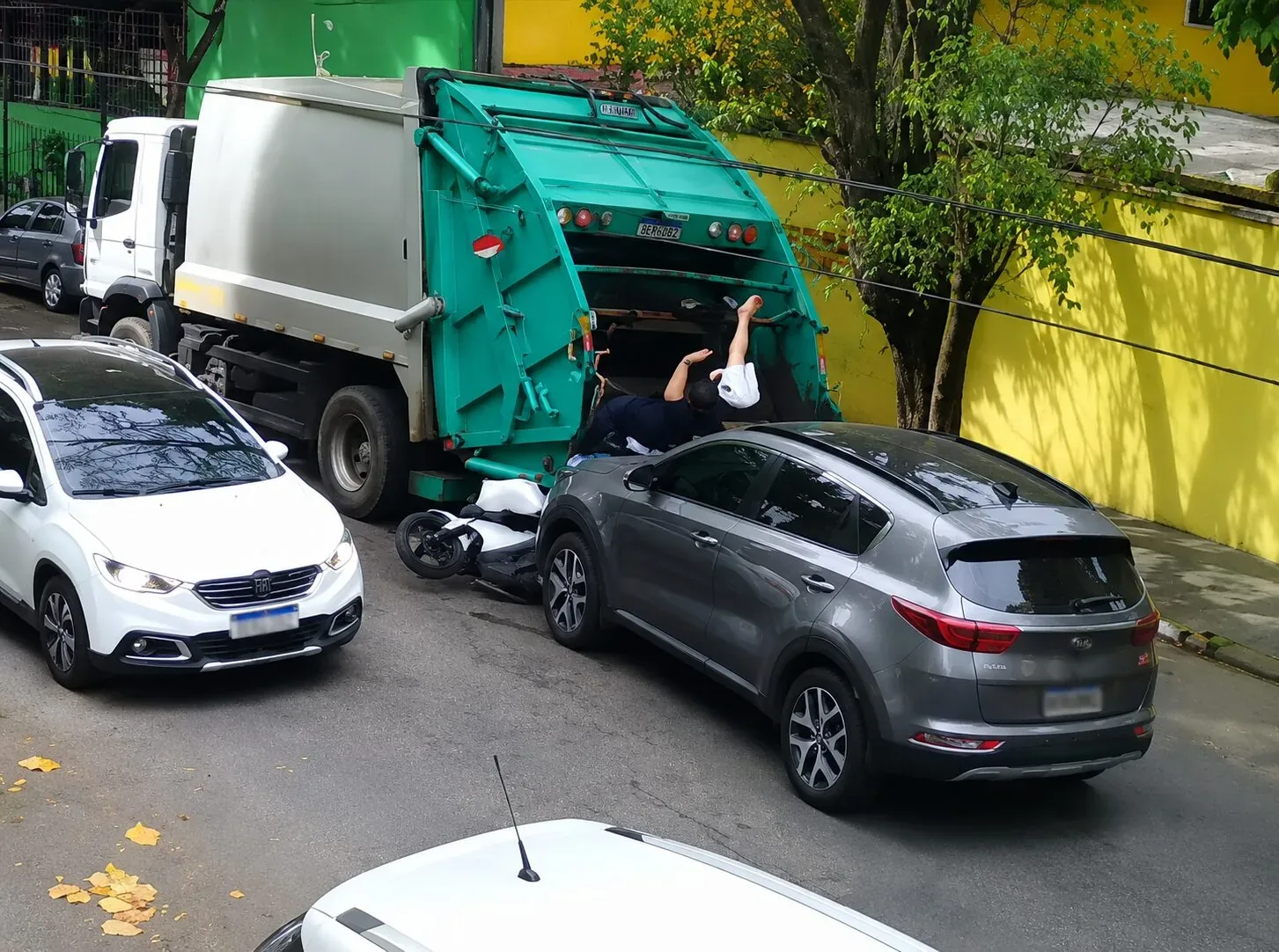 Motociclista cai em caminhão de lixo após colisão; veja vídeo